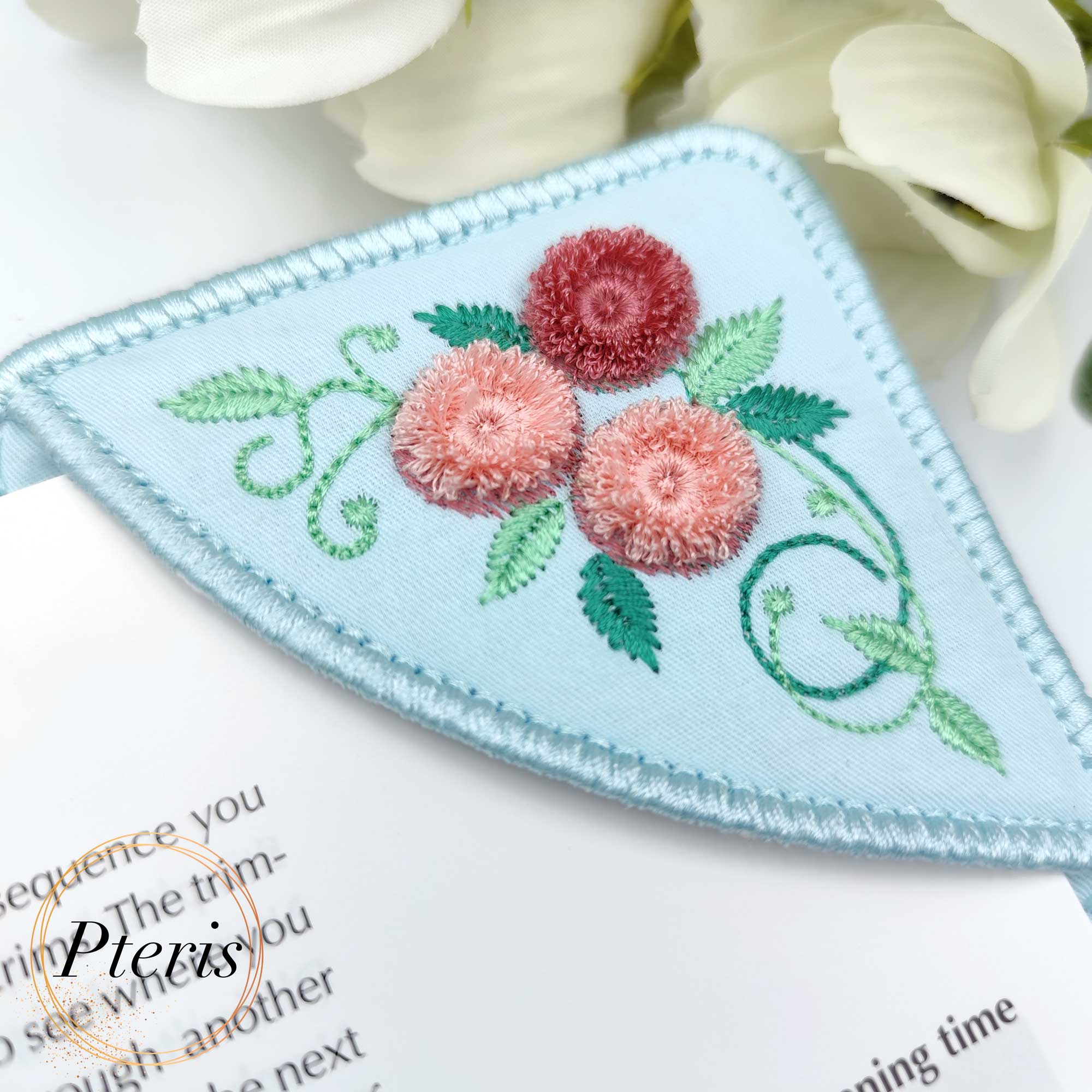 ITH Corner Bookmark embroidery design with 3D pink chenille and fringe roses on light blue fabric