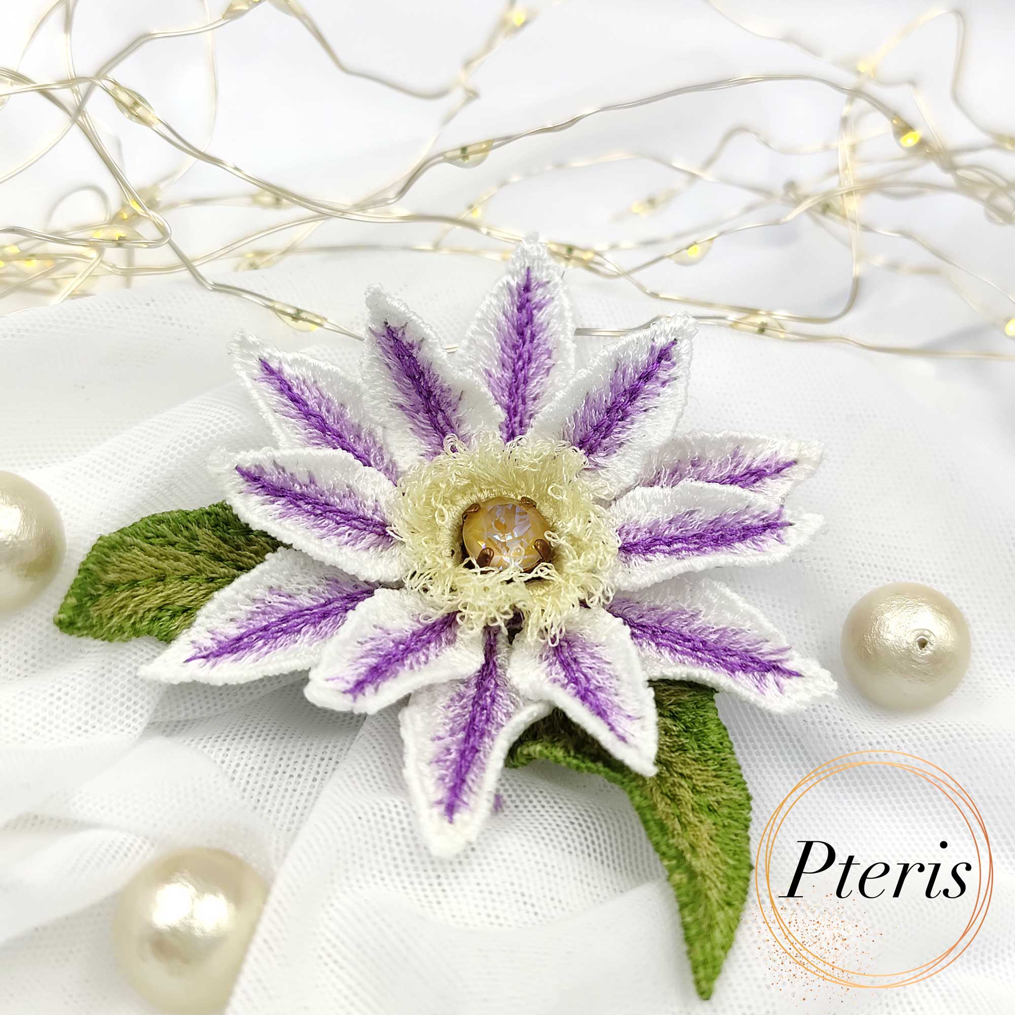 3D Clematis Embroidery Design for FSL brooch featuring white petals with purple striped details, a yellow textured center, and green leaves.