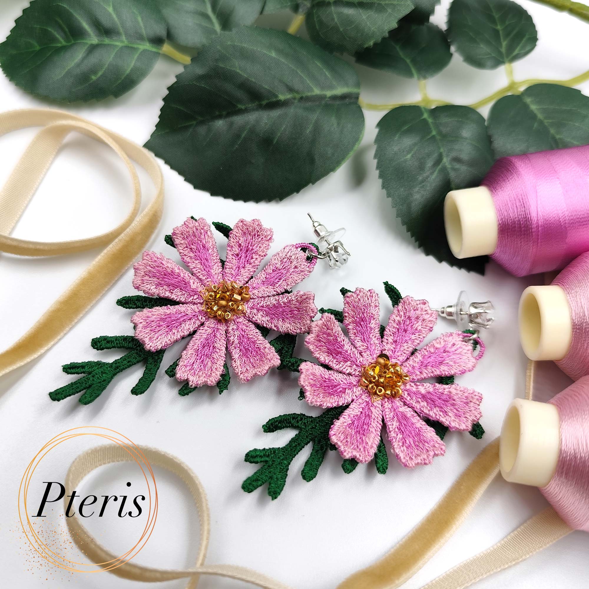 3D Cosmos Embroidery Design for FSL jewelry featuring bright pink petals, golden beaded centers, and green textured leaves on crystal stud earrings.