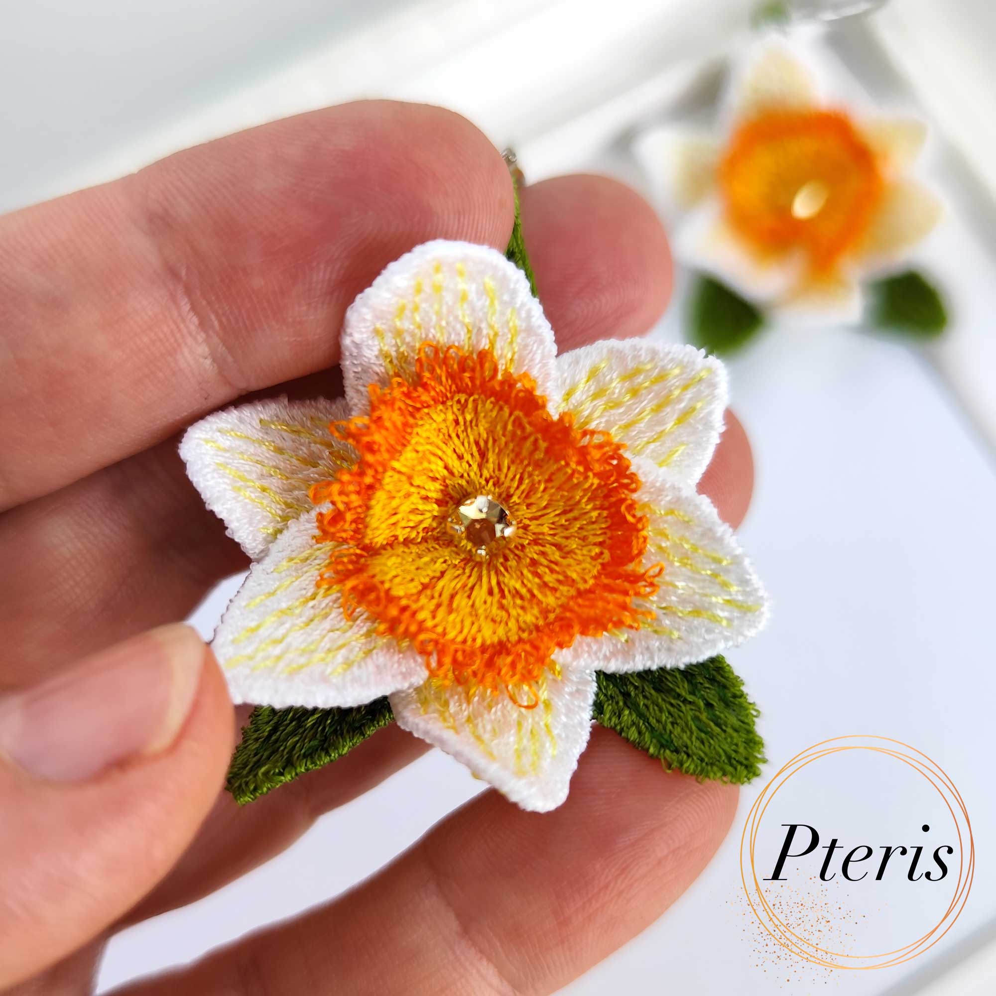 FSL 3D Daffodil earrings machine embroidery design with white and orange petals and green leaves on silver hooks.