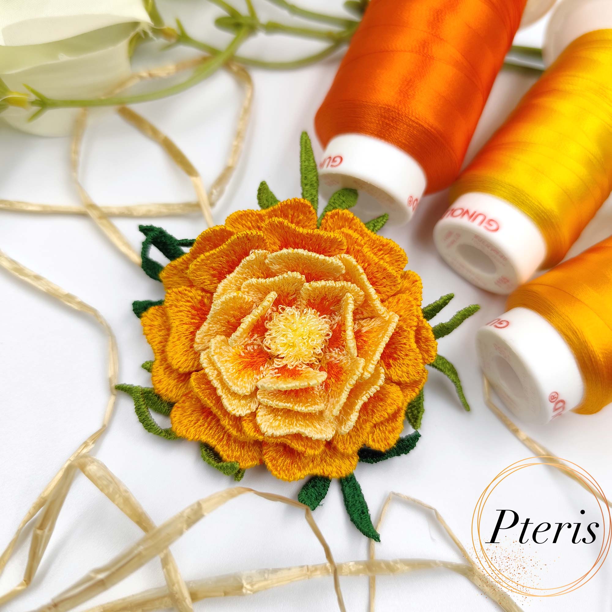 3D Marigold Embroidery Design for FSL brooch featuring layered orange and yellow ruffled petals with dark green leaves.