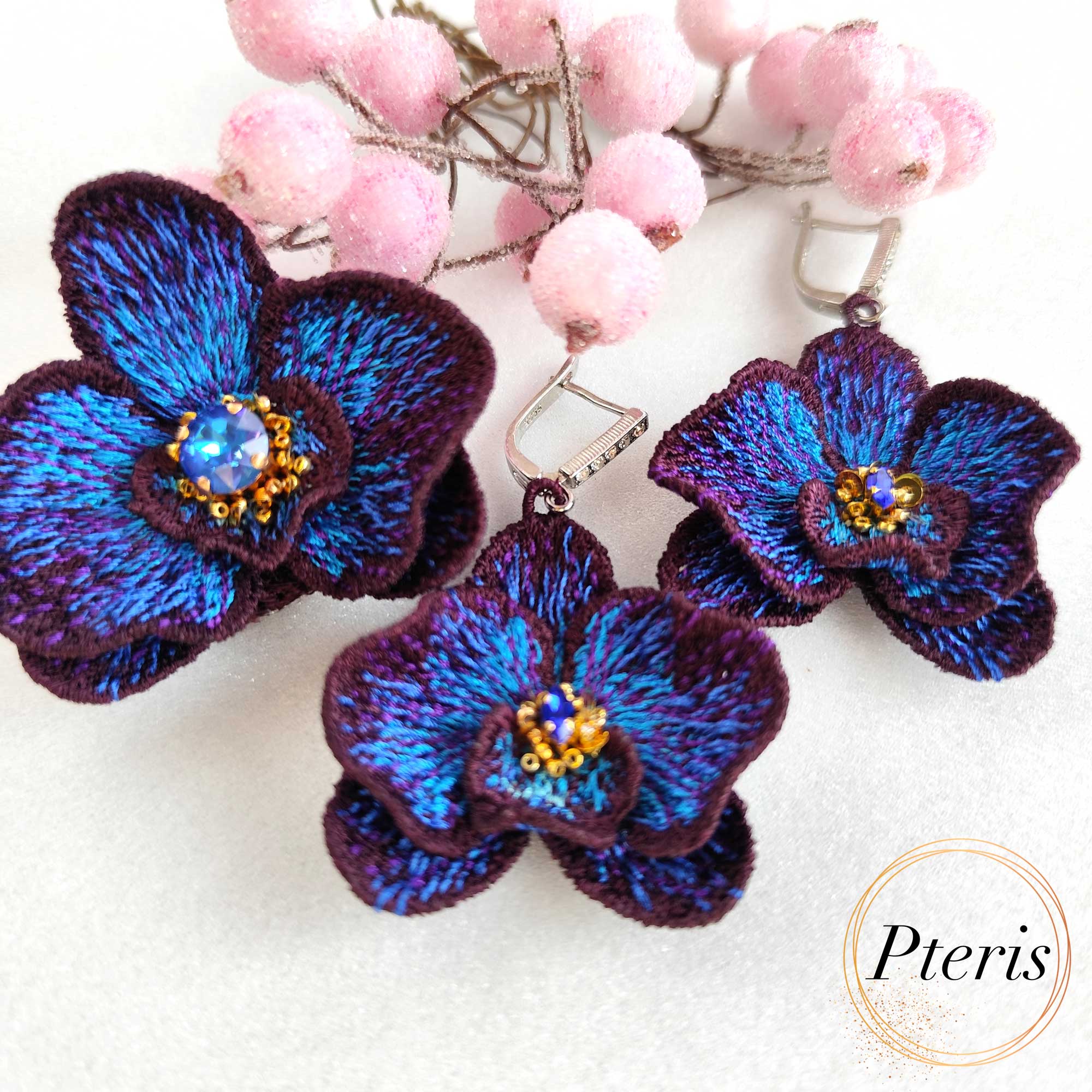 FSL 3D Orchid earrings and brooch machine embroidery design featuring dark purple and bright blue gradient petals with a central crystal accent.