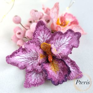 3D Orchid Embroidery Design for FSL brooch featuring layered purple and magenta petals with detailed white veining and an orange textured center.