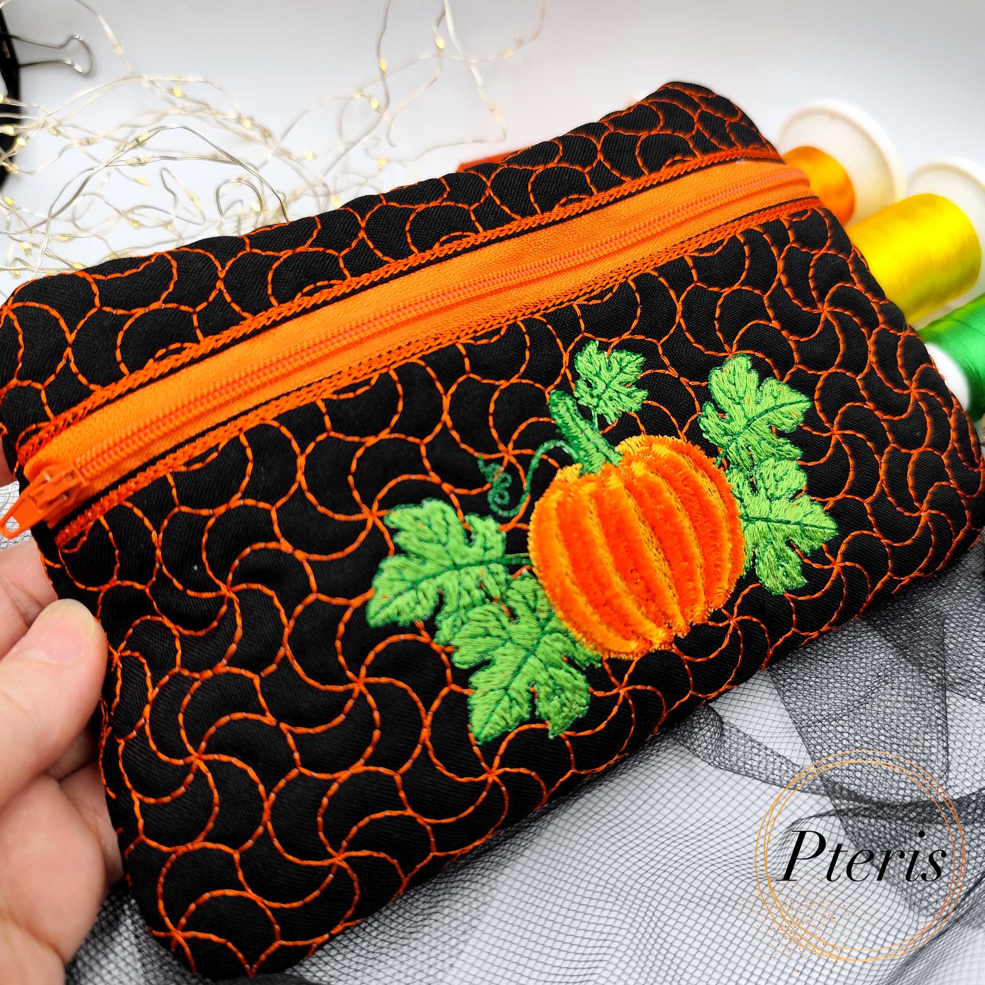 Add a festive touch to your autumn décor with our Fringed Pumpkin Zipper Pouch ITH design. The standout feature of this bag is the central pumpkin motif, created using a specialized fringe technique that gives the pumpkin a soft, 3D textured appearance. Complemented by vibrant green leaves and a unique swirling quilt pattern that mimics vines, this pouch is a masterpiece of seasonal embroidery.