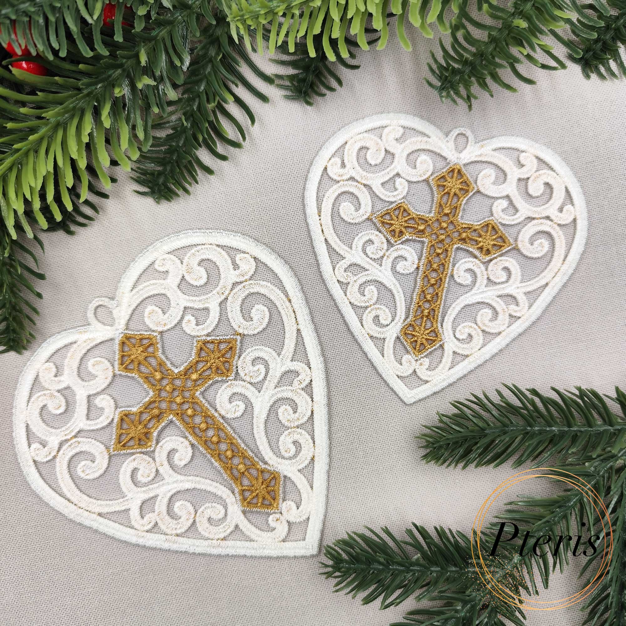 FSL Heart with Cross Suncatcher embroidery design featuring two white freestanding lace hearts with intricate gold crosses, styled with evergreen branches and red berries.