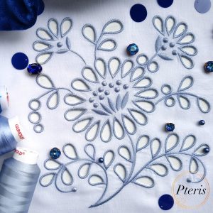 Detailed Richelieu cutwork machine embroidery design featuring blue floral motifs and openwork on white fabric, styled with blue thread spools and sparkling crystals.