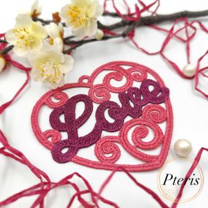 FSL Love Heart Suncatcher embroidery design featuring a pink and purple freestanding lace heart with "Love" script, styled with white spring blossoms and pearls.