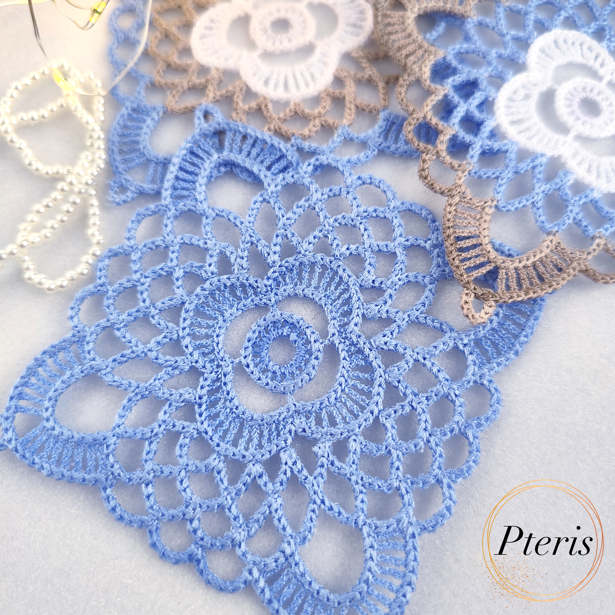 FSL Granny Square Crochet Design featuring freestanding lace coasters with a white central flower, light blue inner petals, and a beige scalloped border.
