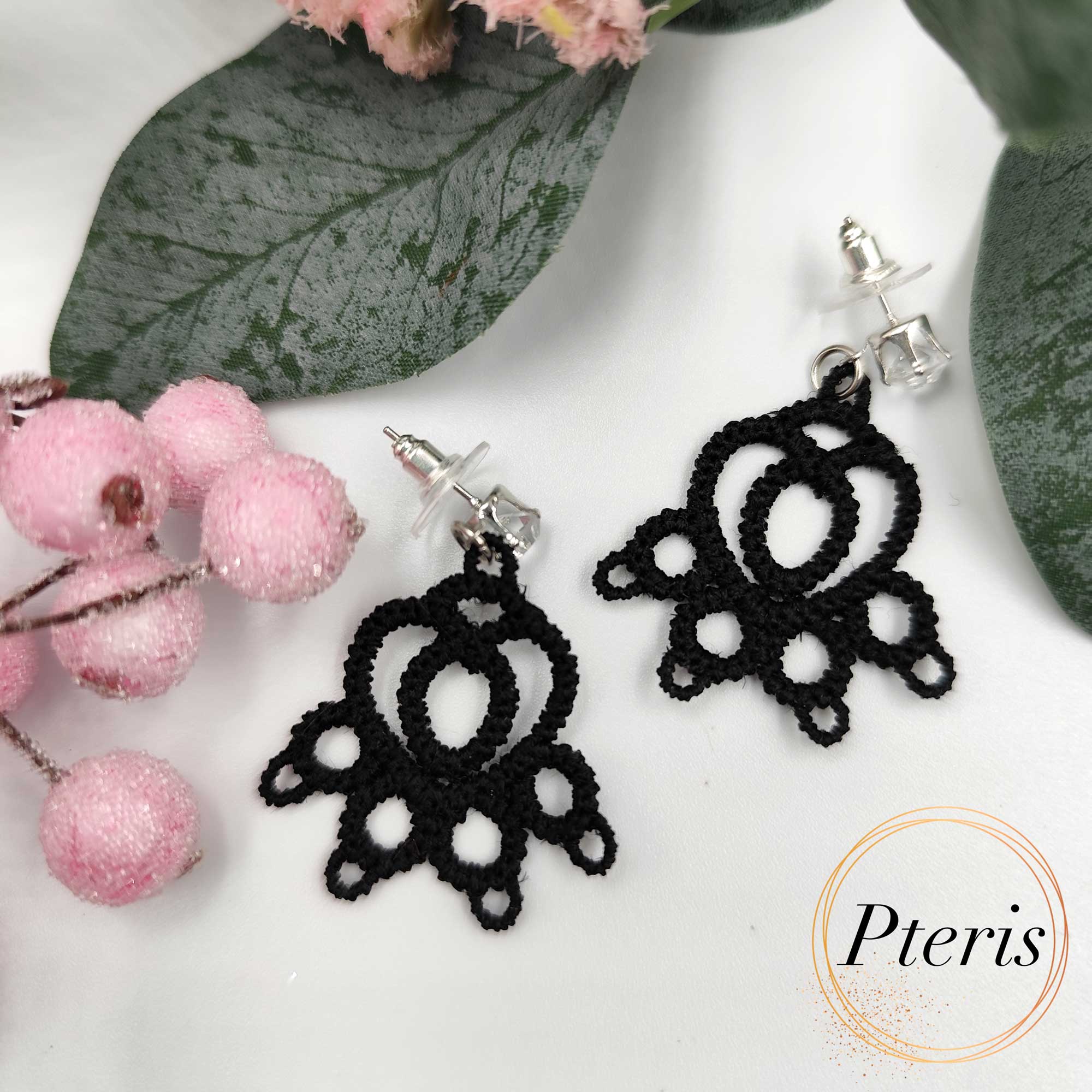 FSL Cat Paw Earrings Embroidery Design showing a pair of black tatting-style lace earrings shaped like cat paws on a white background with decorative leaves and berries.