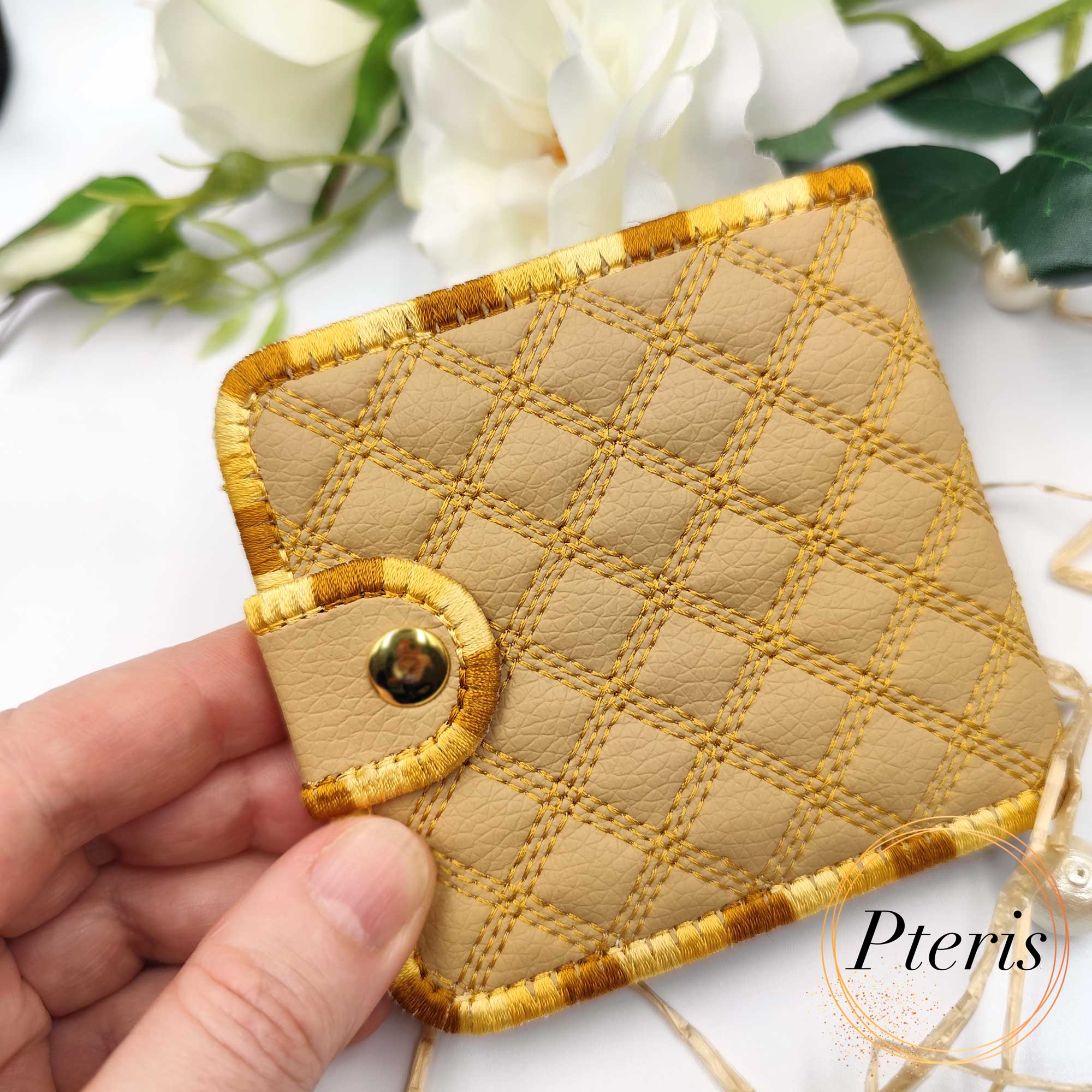 ITH Quilted Wallet embroidery design showing a handmade bifold wallet with blue diamond quilting, credit card slots, and a bill compartment, styled with a blue thread spool.