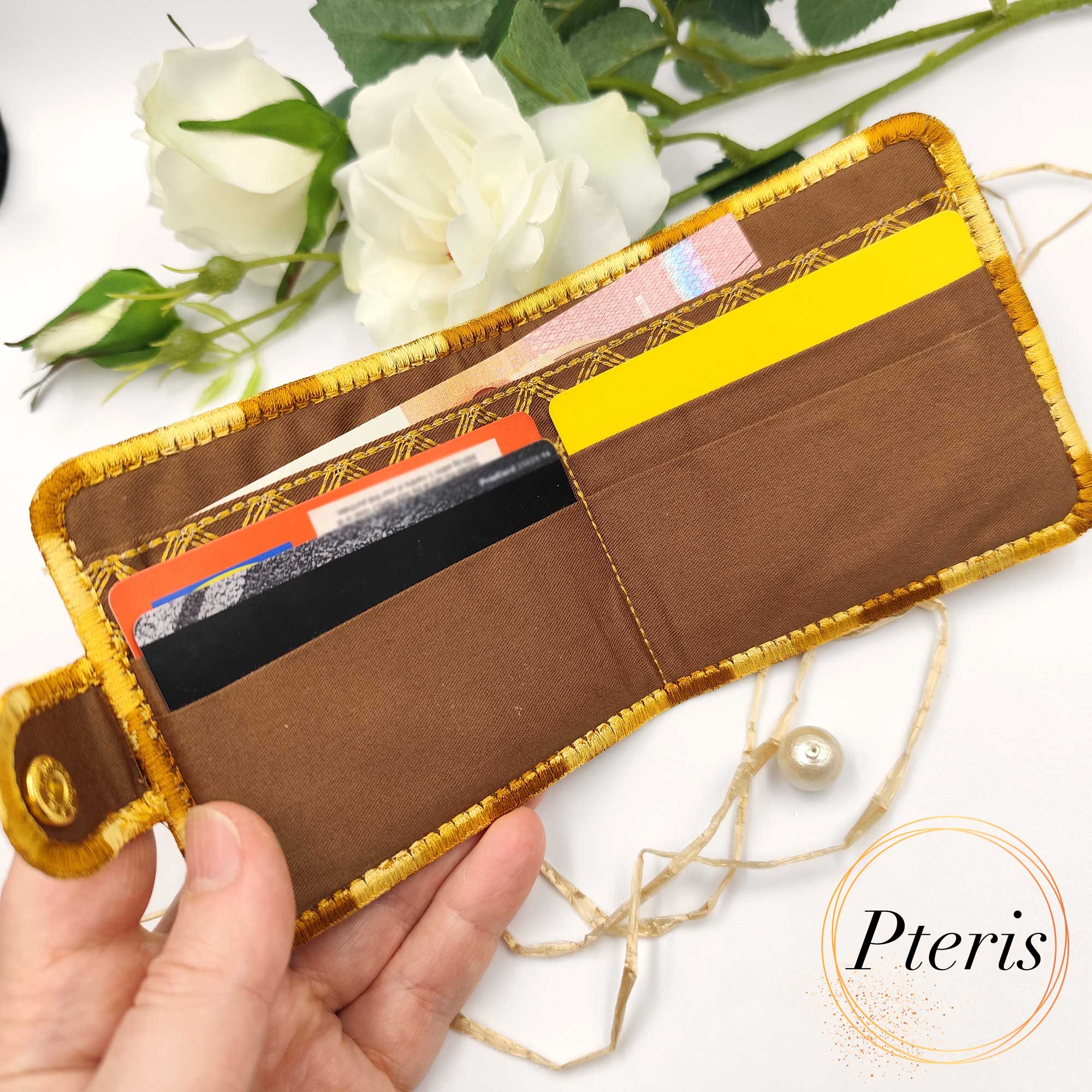 ITH Quilted Wallet embroidery design showing a handmade bifold wallet with blue diamond quilting, credit card slots, and a bill compartment, styled with a blue thread spool.
