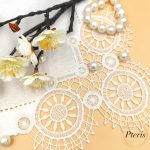 FSL Lace Napkin Corner embroidery design featuring white freestanding lace circular motifs stitched onto a linen napkin, styled with pearls and white blossoms on a peach background.