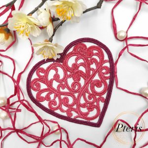 FSL Filigree Heart Suncatcher embroidery design featuring a pink freestanding lace heart with intricate scrolls, styled on a white background with pine branches and Christmas ornaments.