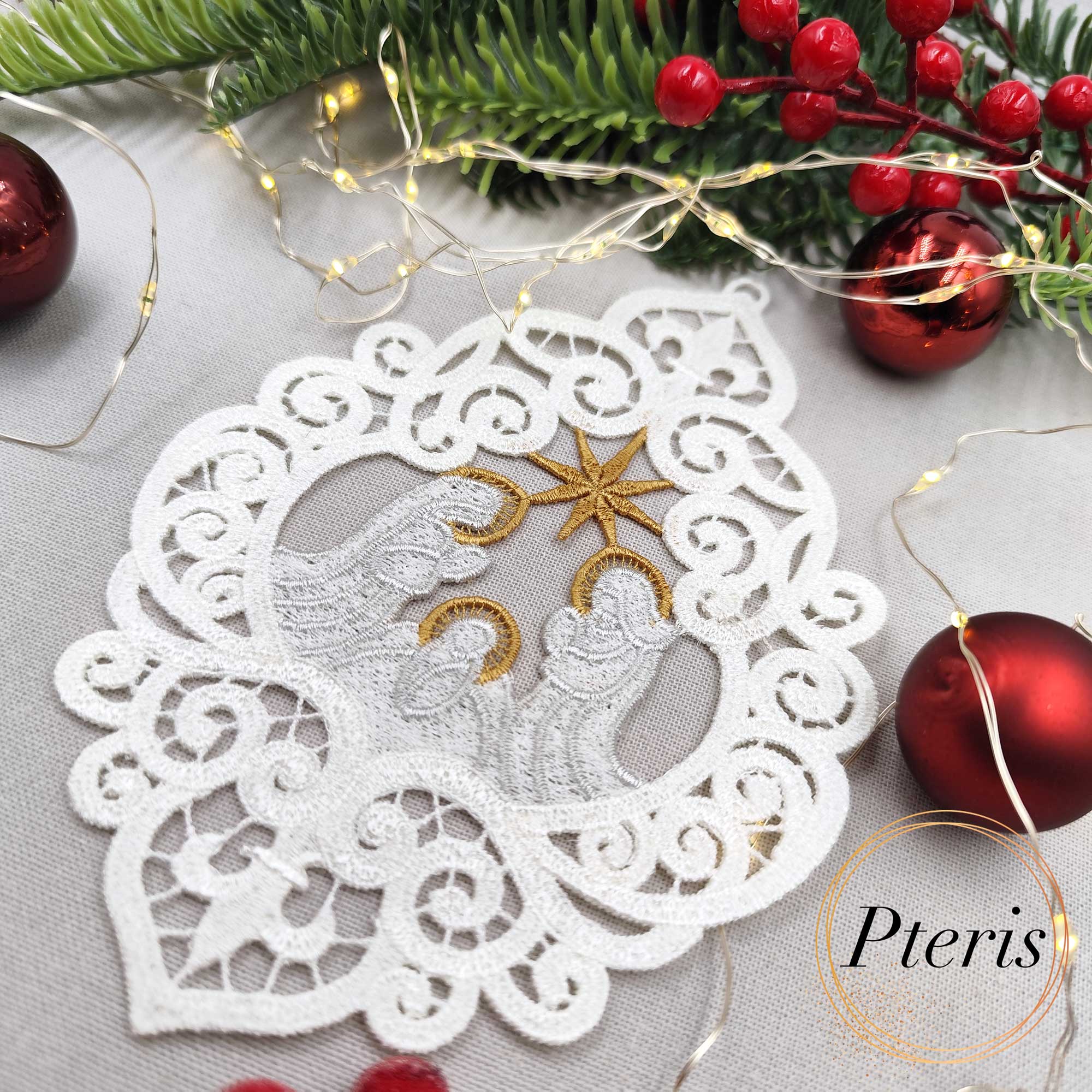 FSL Nativity Scene Suncatcher embroidery design featuring a white and gold freestanding lace ornament of the Holy Family, styled on a grey background with pine branches, red ornaments, and fairy lights.
