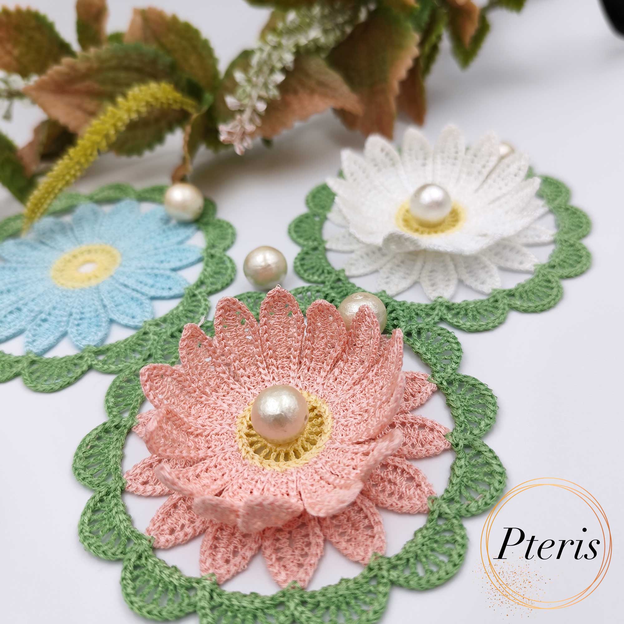 FSL 3D Daisy Embroidery Design featuring three crochet-style doilies in white, pink, and blue with 3D petals and pearl centers, arranged on a white background with green lace borders