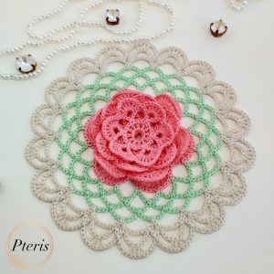 FSL 3D Rose Doily Embroidery Design featuring a pink 3D lace rose centered on a green and beige crochet-style freestanding lace doily, styled with pearls.