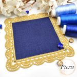 FSL Crochet Style Napkin Design featuring a square navy blue linen center surrounded by an intricate gold freestanding lace border, displayed with blue embroidery threads.