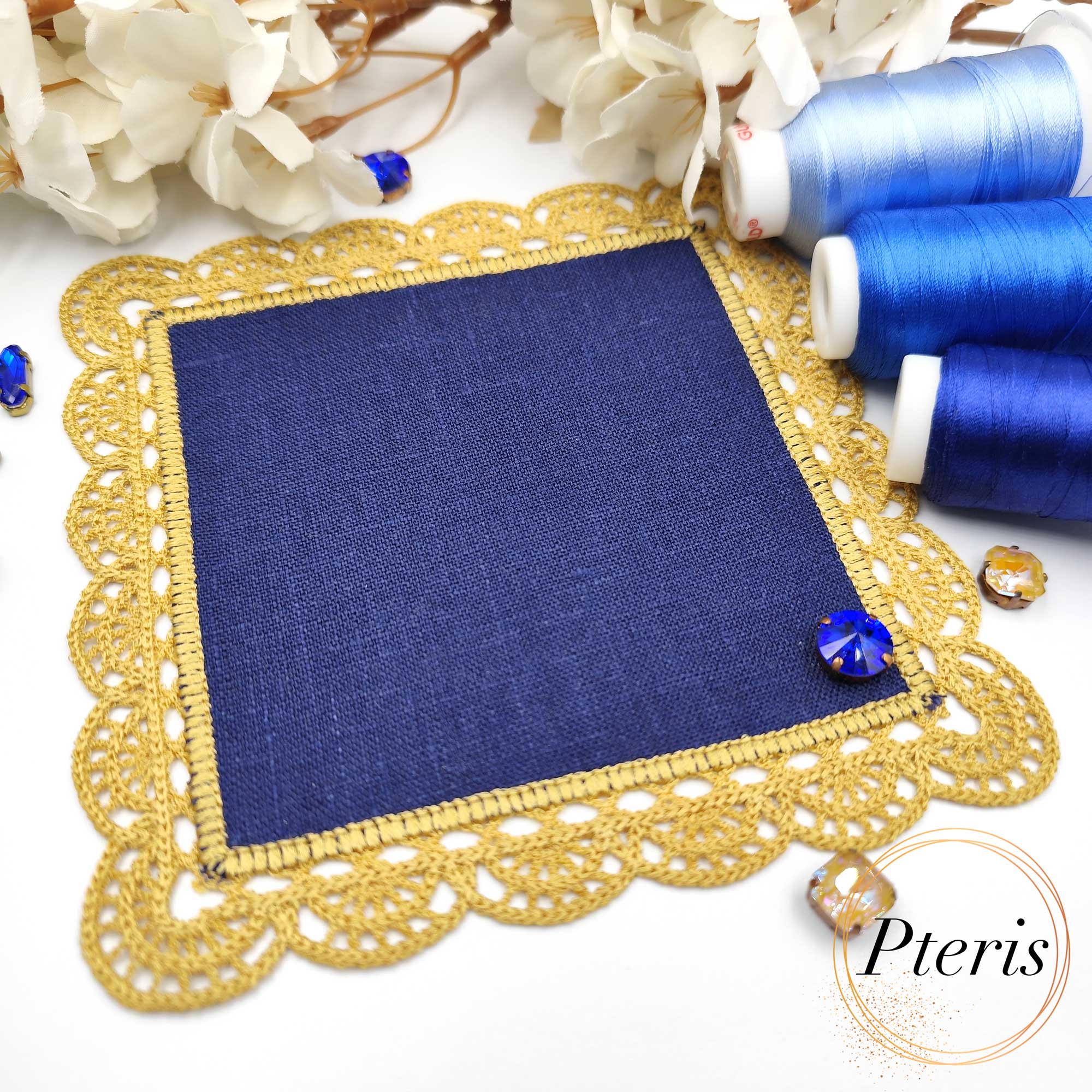 FSL Crochet Style Napkin Design featuring a square navy blue linen center surrounded by an intricate gold freestanding lace border, displayed with blue embroidery threads.