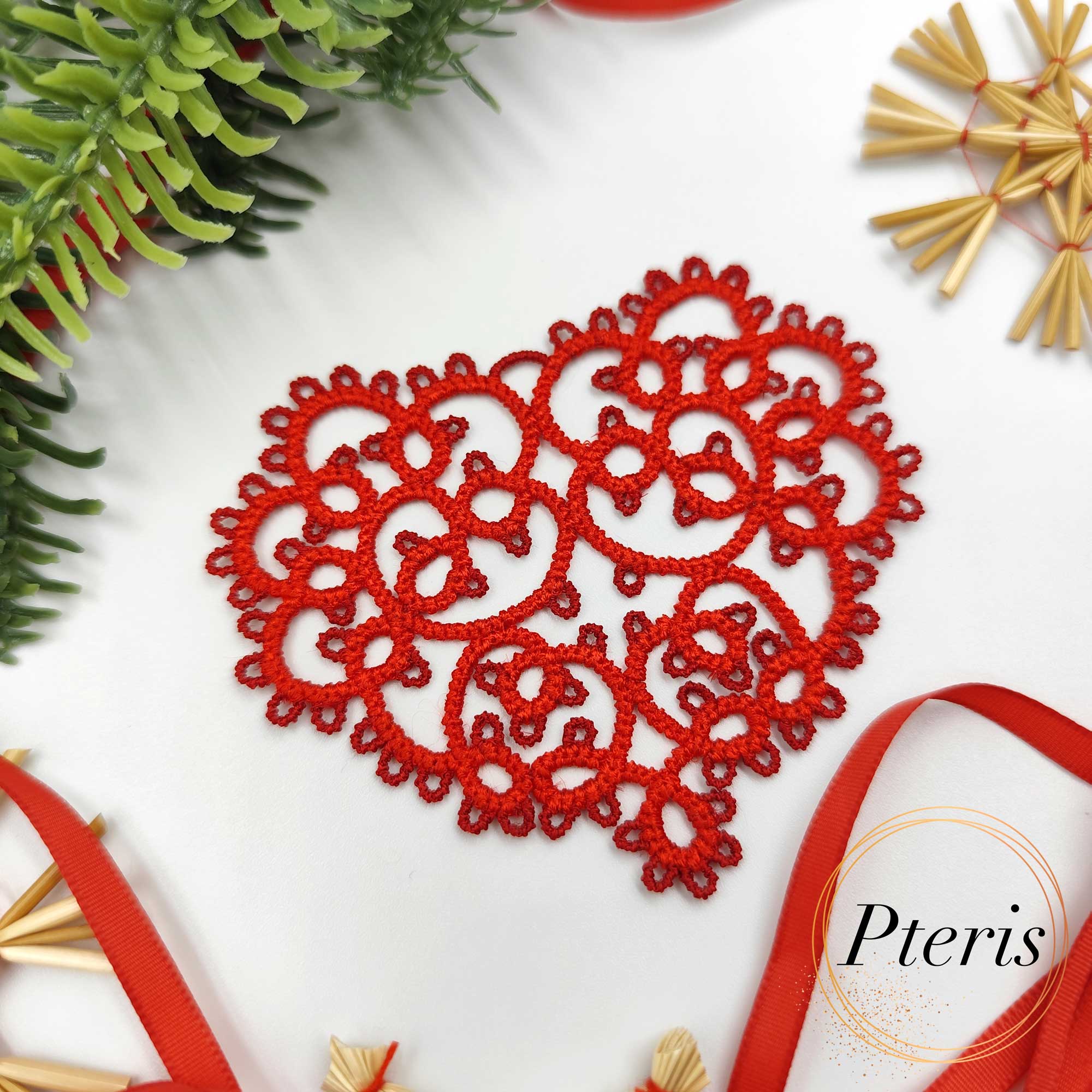 FSL Tatting Heart Pendant Design featuring a bright red freestanding lace heart ornament suspended by a ribbon, surrounded by festive evergreen branches and straw stars.