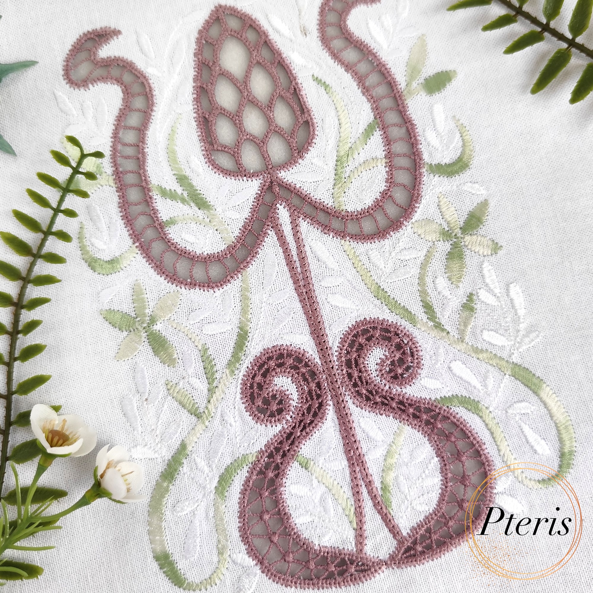 Cutwork Protea machine embroidery design showing a close-up of an intricate, stylized protea flower stitched in dusty rose and sage green thread on white linen fabric, featuring delicate Richelieu cutwork lace netting windows.