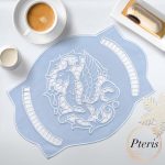 Gryphon Richelieu cutwork doily machine embroidery design featuring an intricate linen table topper with embroidered mythical gryphon motifs and openwork lace arches, styled flat on a dark background.