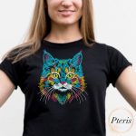 Vibrant rainbow cat portrait machine embroidery design showing a colorful feline face with green eyes, neon blue, yellow, and pink fur lines, stitched onto the front of a casual black cotton t-shirt.