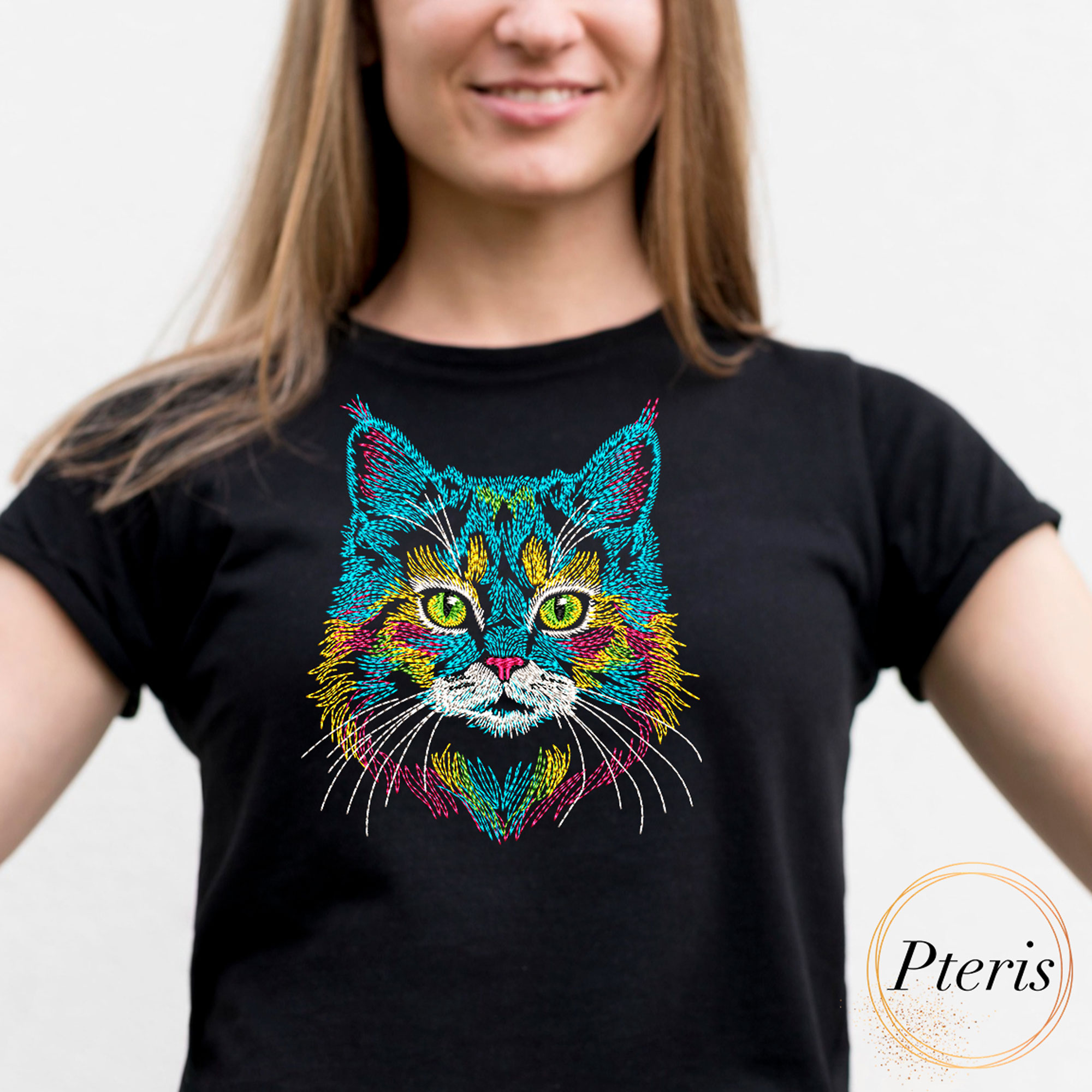Vibrant rainbow cat portrait machine embroidery design showing a colorful feline face with green eyes, neon blue, yellow, and pink fur lines, stitched onto the front of a casual black cotton t-shirt.
