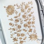 An elegant, monochrome botanical machine embroidery design featuring delicate daisies and meadow grasses stitched with a golden-beige thread on white fabric within a grey hoop, as shown in Daisy-and-Meadow-Grasses-Infinity-Border-Machine-Embroidery-Design-