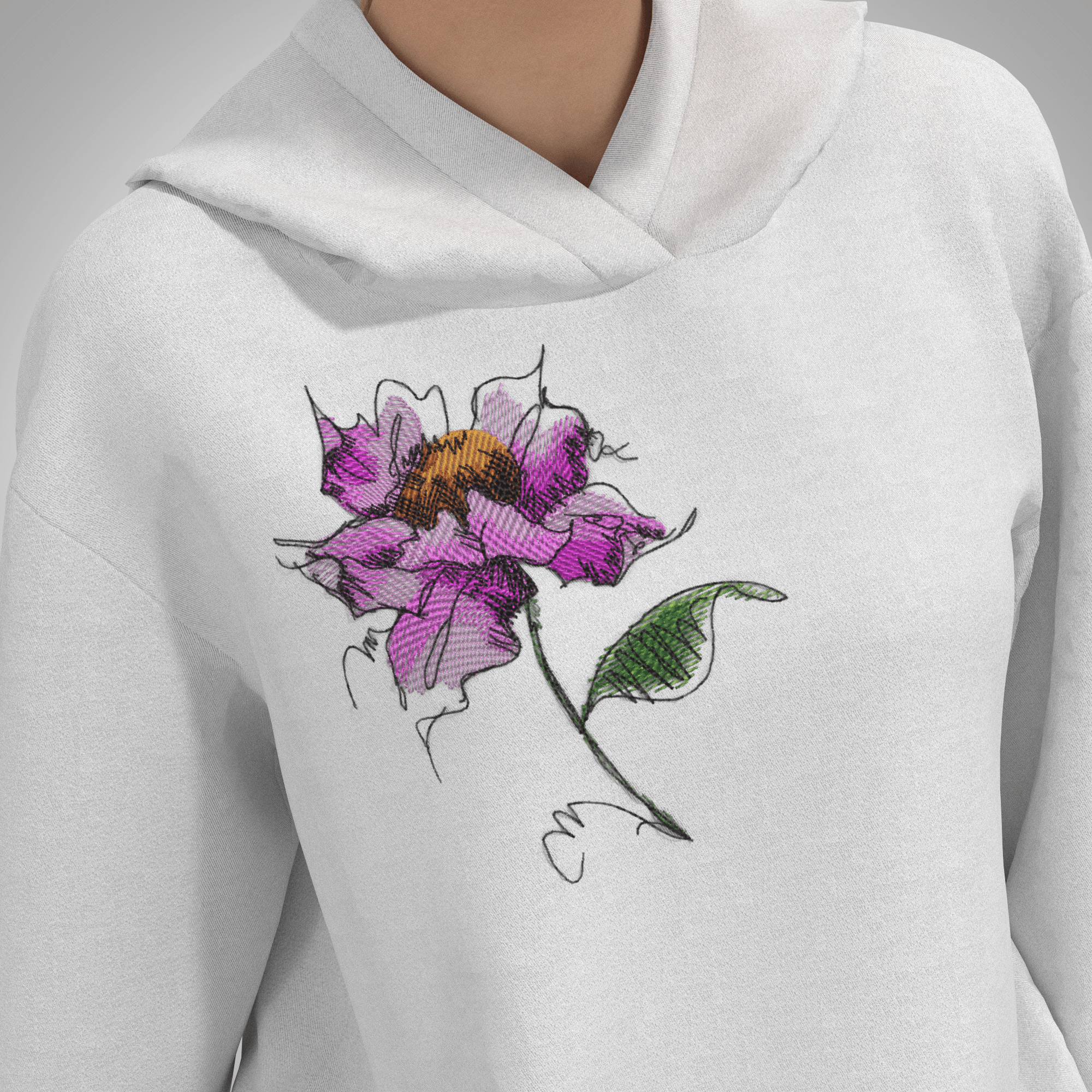An artistic sketch-style machine embroidery design of a pink watercolor-effect flower with an orange center and a green leaf, stitched on the chest of a white hooded sweatshirt, as shown in Watercolor Flower Machine Embroidery Design